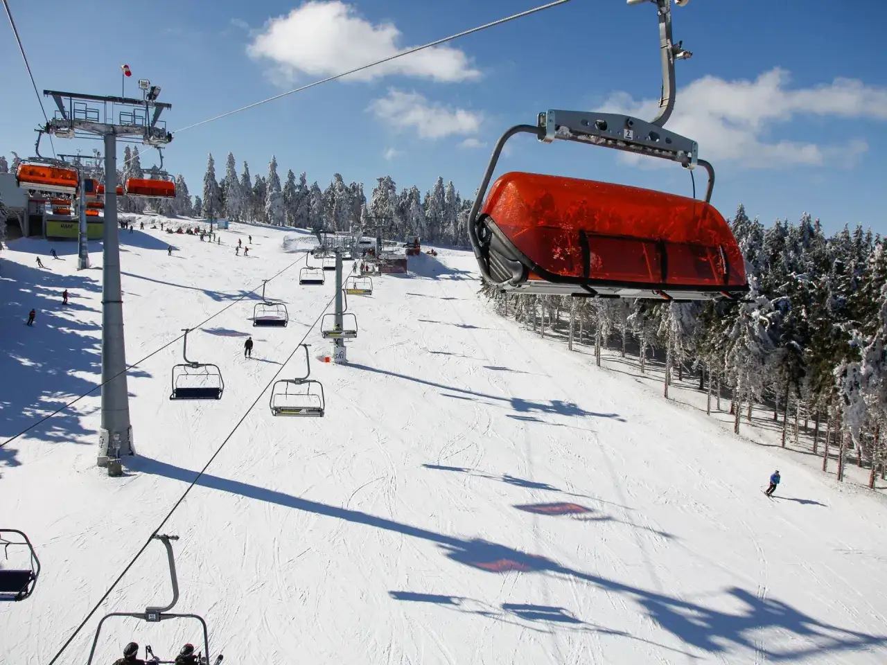 Widok na stok narciarski w Zieleńcu z wyciągiem krzesełkowym. Widać wiele tras narciarskich, idealnych do jazdy na nartach.