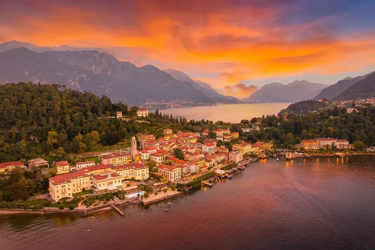 Zach&oacute;d słońca nad Jeziorem Como, idealne miejsce na wycieczkę. Wioska z kolorowymi domami i g&oacute;rami w tle.