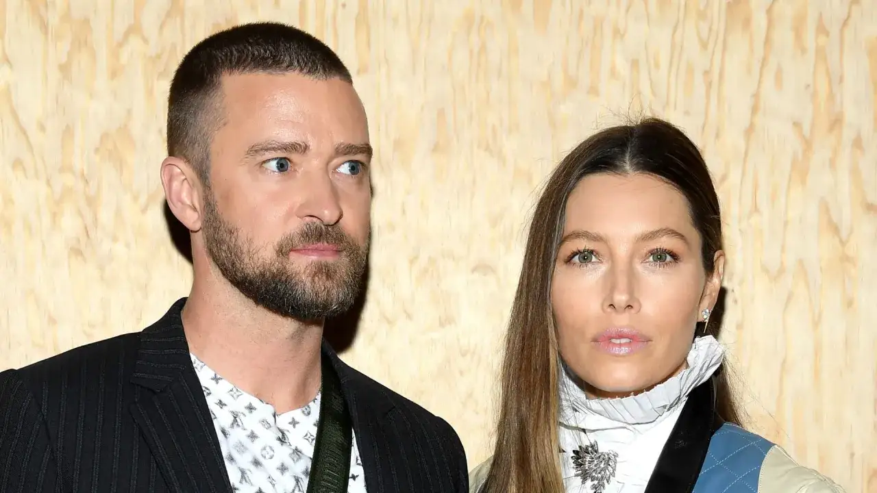 Jessica Biel i Justin Timberlake pozują do zdjęcia na tle drewnianej ściany.