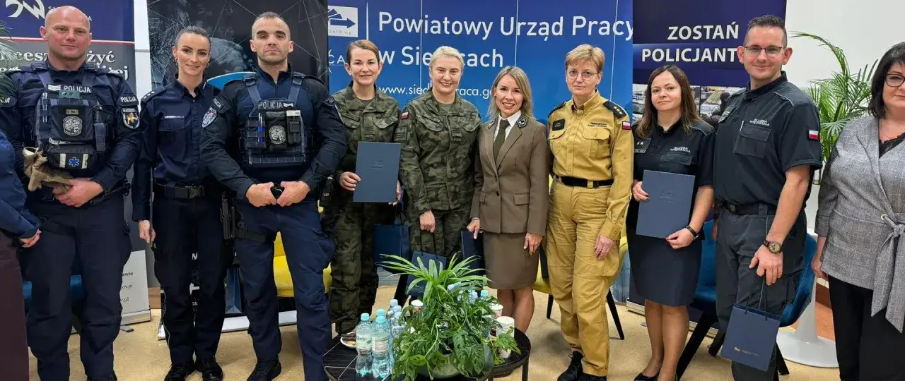 Grupa osób w mundurach, w tym policjanci i żołnierki, pozuje do zdjęcia. Wszyscy prezentują się profesjonalnie, podkreślając znaczenie służby mundurowej.