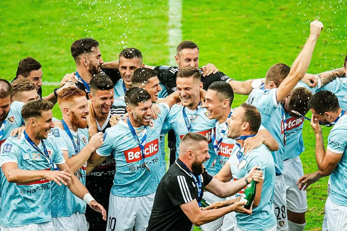 Radosny tłum piast gliwice zawodnicy świętuje zwycięstwo, sypiąc konfetti i otwierając szampana.
