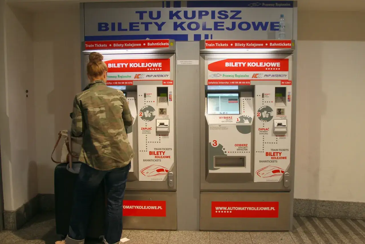 Kobieta kupuje bilety kolejowe na pociąg do Krakowa w automacie PKP Intercity.