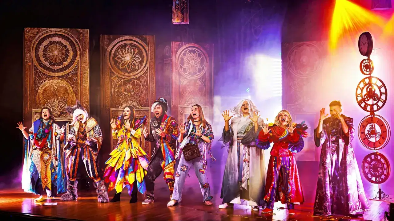 Aktorzy w barwnych strojach na scenie, przygotowujący się do spektaklu. To teatr dla nastolatków, pełen magii i kolorów.