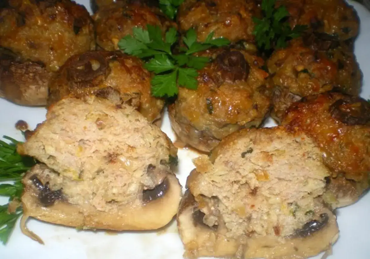 Pyszne pieczarki nadziewane mięsem mielonym, zapieczone ze złotą sk&oacute;rką, ozdobione natką pietruszki.