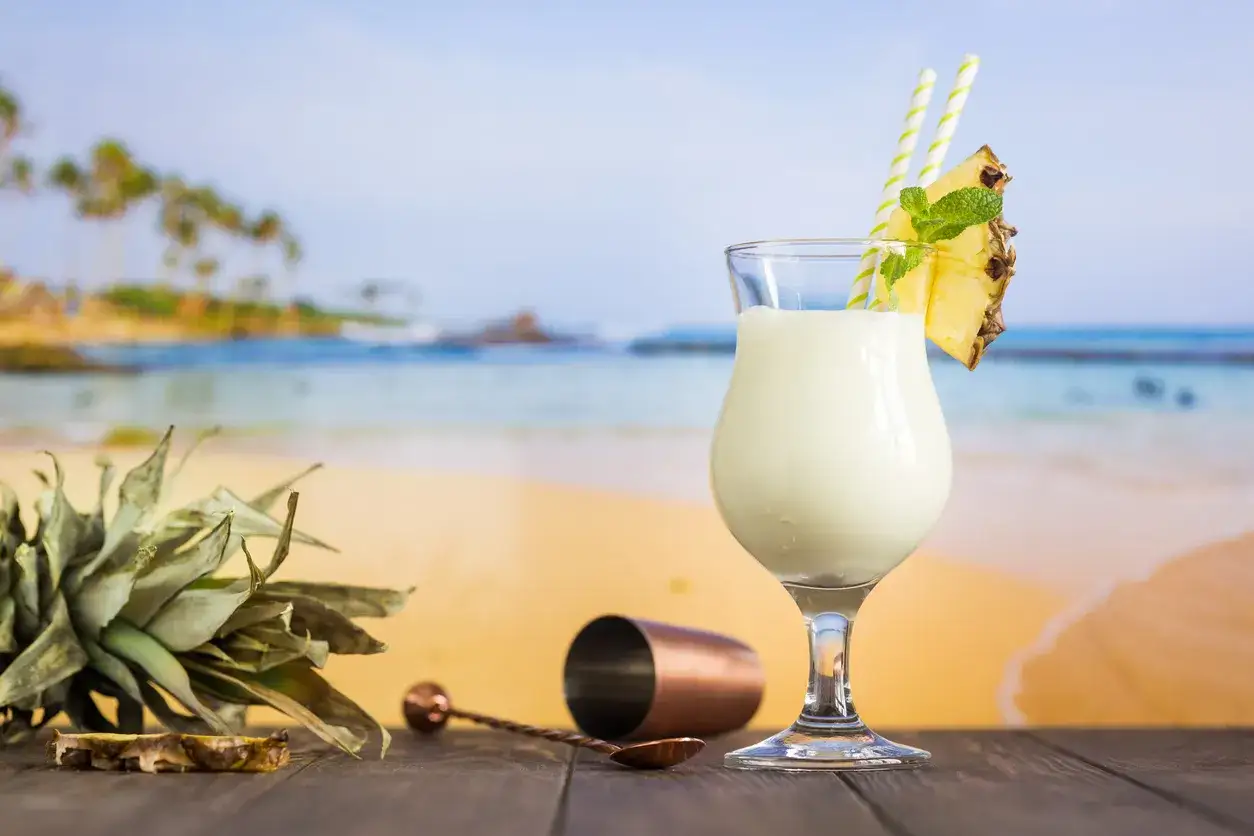 Pina Colada przepis na tropikalne orzeźwienie. Kremowy koktajl z ananasem i miętą na plaży.