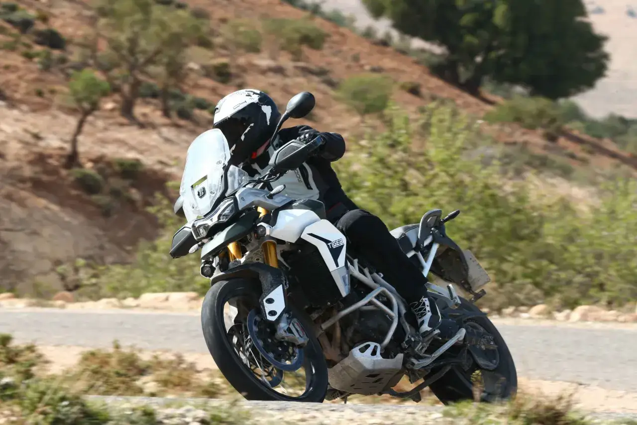Motocyklista na motocyklu Tiger 900 GT Pro pokonuje zakręt na g&oacute;rskiej drodze.