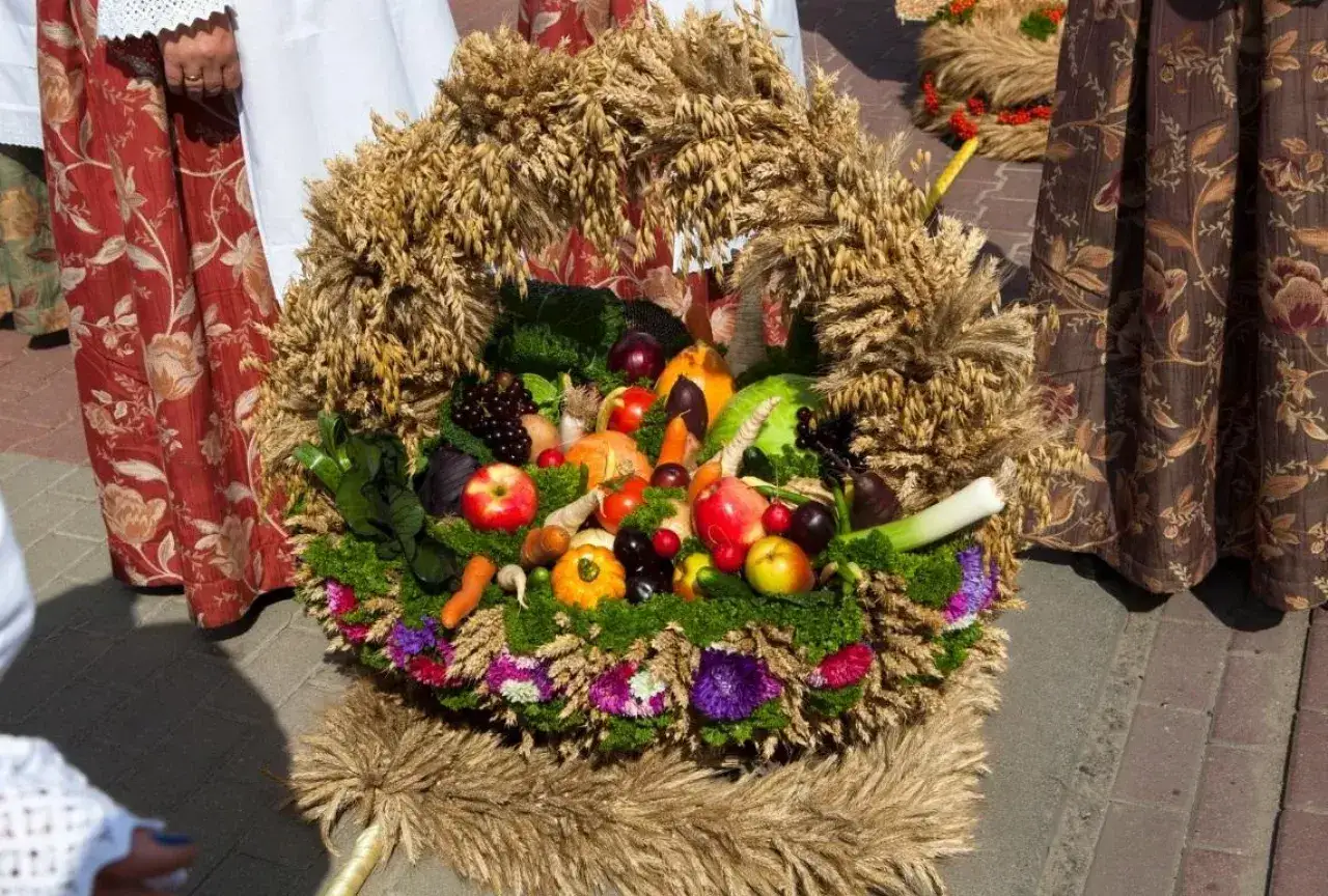 Wieniec dożynkowy pełen owoców, warzyw i zbóż. Inspiracja, jak zrobić kwiaty do wieńca dożynkowego, widoczna w jego bogactwie.