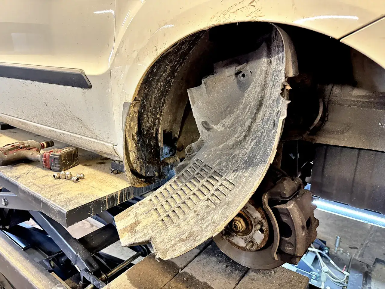 Naprawa odkształconego plastiku nadkola. Widać narzędzia i elementy do naprawy.