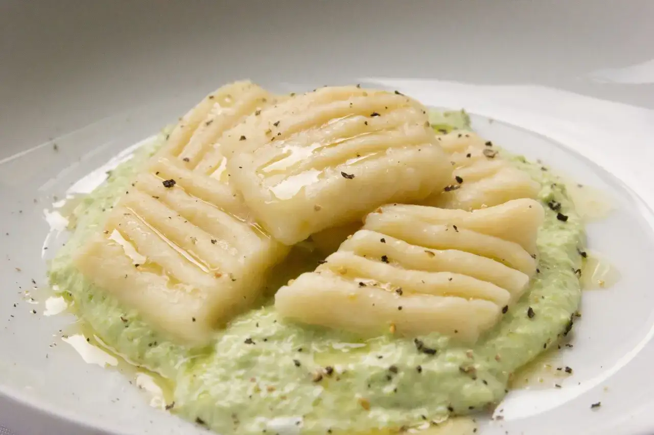 Pyszne kopytka na obiad, polane zielonym sosem i posypane pieprzem. Idealne danie dla każdego.