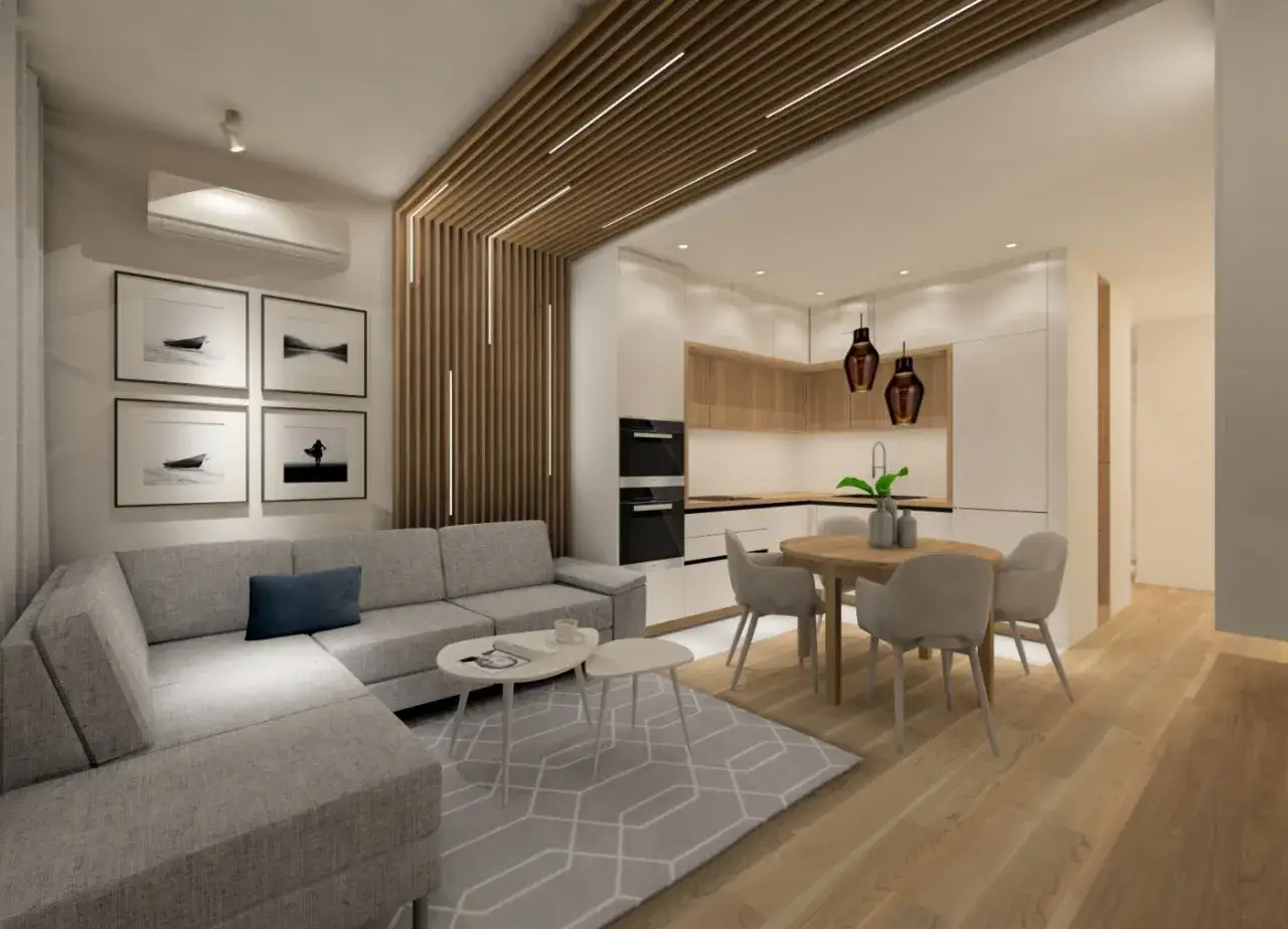Nowoczesny salon z aneksem kuchennym, gdzie oświetlenie w lamelach tworzy ciepłą atmosferę. Szara sofa, okrągły st&oacute;ł i drewniane akcenty.