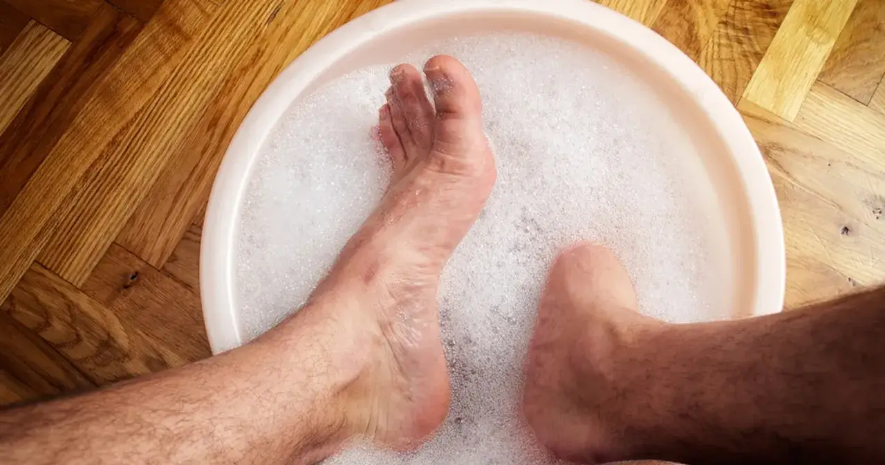 Kąpiel st&oacute;p w wodzie z octem, bąbelki unoszą się na powierzchni. Domowy spos&oacute;b na odświeżenie.