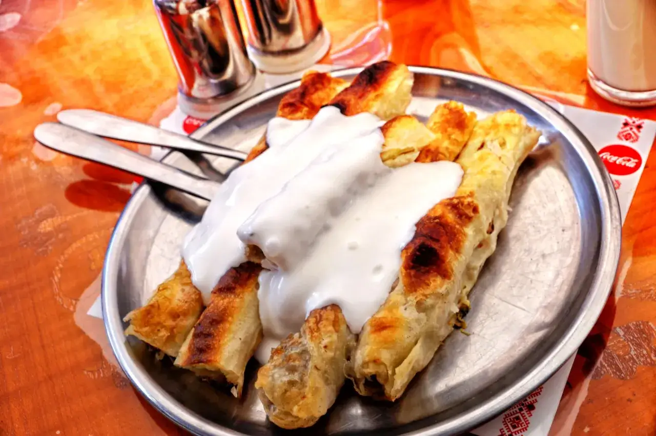 Pyszne danie kuchni bośniackiej: pieczone ciasto z mięsem, polane gęstym jogurtem. Idealne na szybki posiłek.