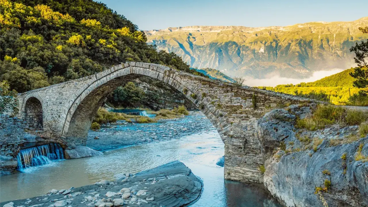 Kamienny most w Albanii, z wodospadem i górami w tle. Permet Albania.