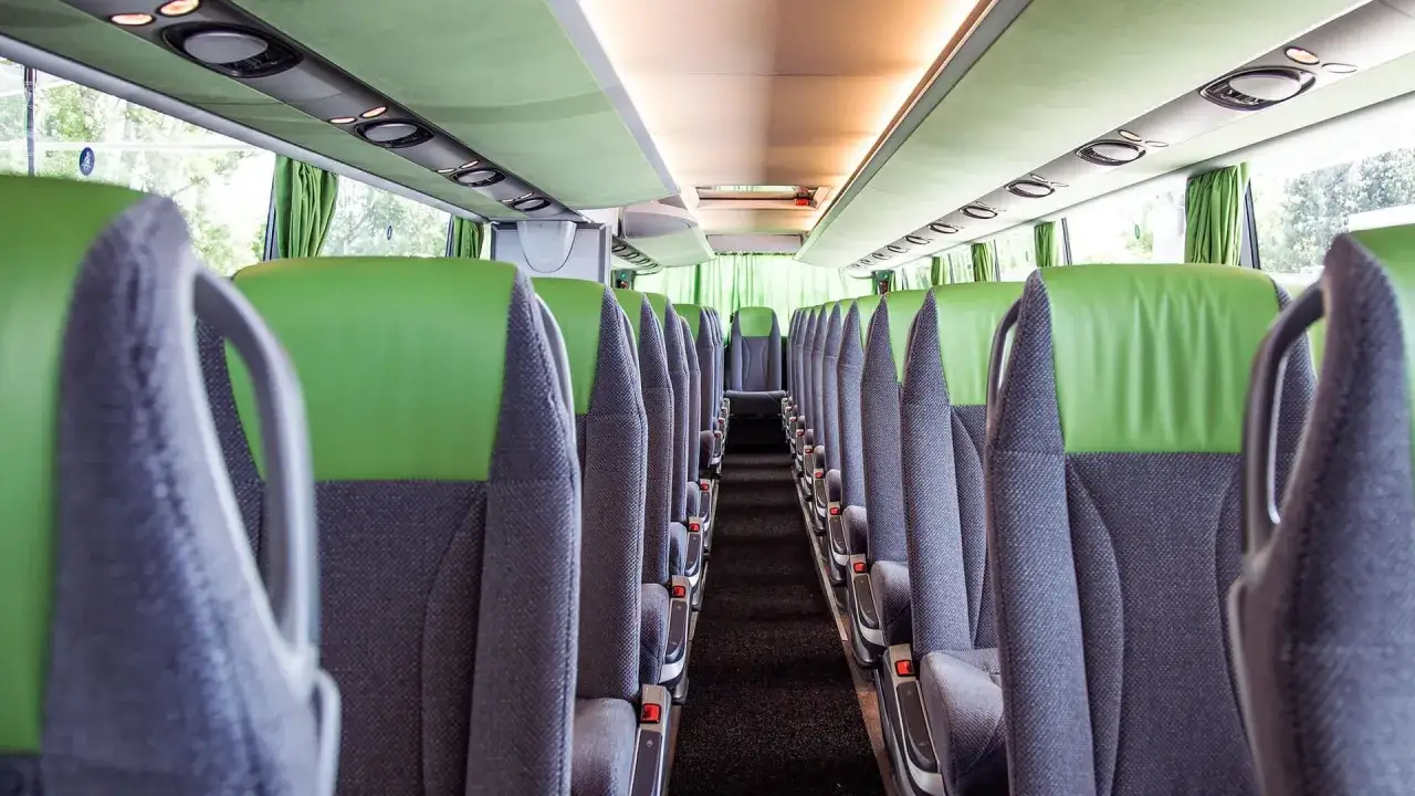 Wnętrze autokaru z zielono-szarymi siedzeniami, gotowego na podróż z Zamościa do Krakowa.