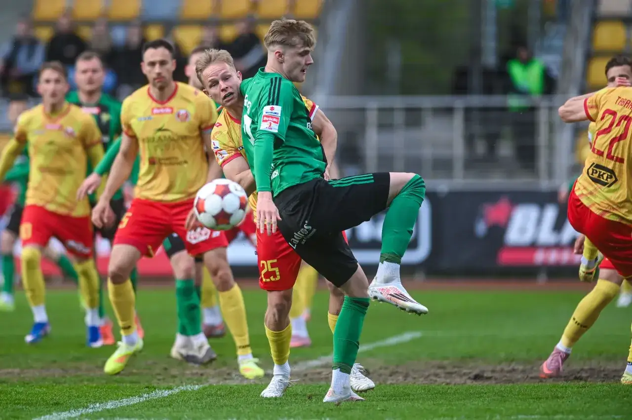 Piłkarze w zielonych i żółtych strojach walczą o piłkę. Czy to oni są tymi, kto spada z ekstraklasy?