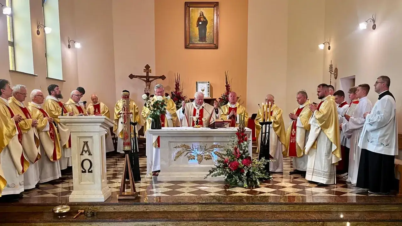 Uroczysta msza święta w kościele. Kapłani w złotych szatach celebrują, a wierni uczestniczą w tym ważnym wydarzeniu, jakim jest konsekracja kościoła.