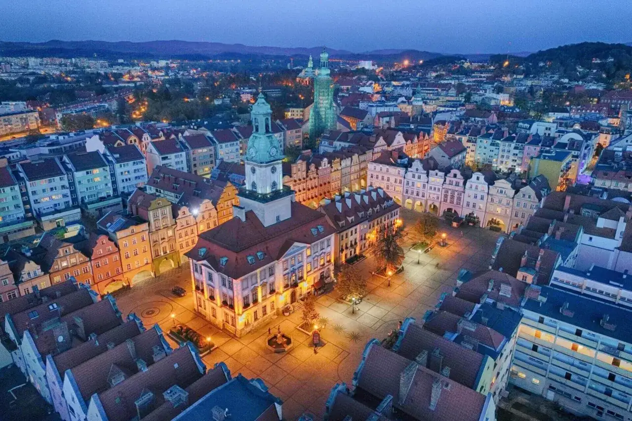 Nocny widok na jeden z najpiękniejszych rynk&oacute;w w Polsce, oświetlony ratusz i kolorowe kamienice tworzą magiczną atmosferę.