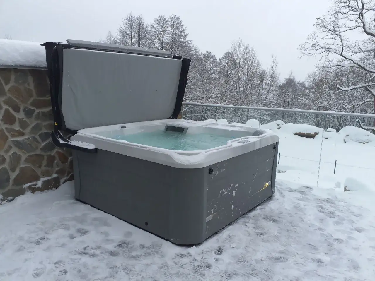 Zimowy relaks w jacuzzi ogrodowym lay z spa. Ciepła woda w otoczeniu śniegu i drzew.
