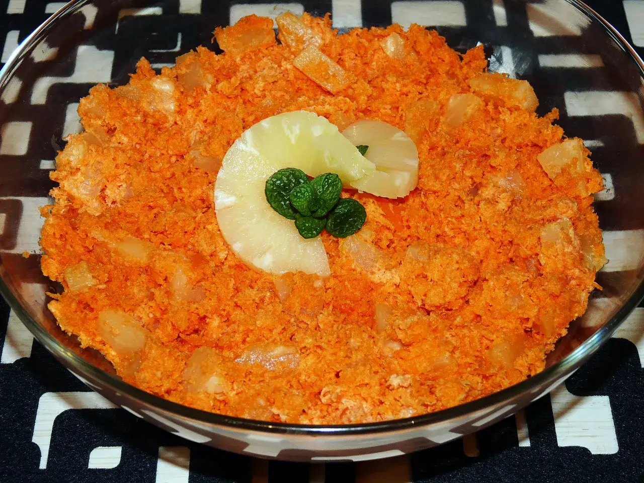 Słodka marchewka z ananasem, udekorowana plasterkiem ananasa i listkami mięty. Idealna na deser.