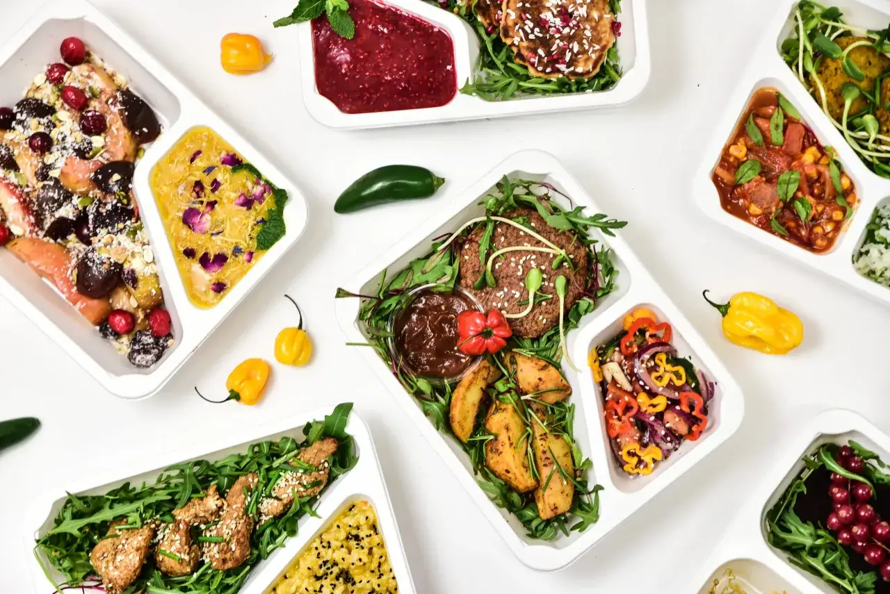 Różnorodne dania w pojemnikach: od owoców z granolą po mięso z ryżem. Zastanawiasz się, ile kosztuje catering dietetyczny na miesiąc?