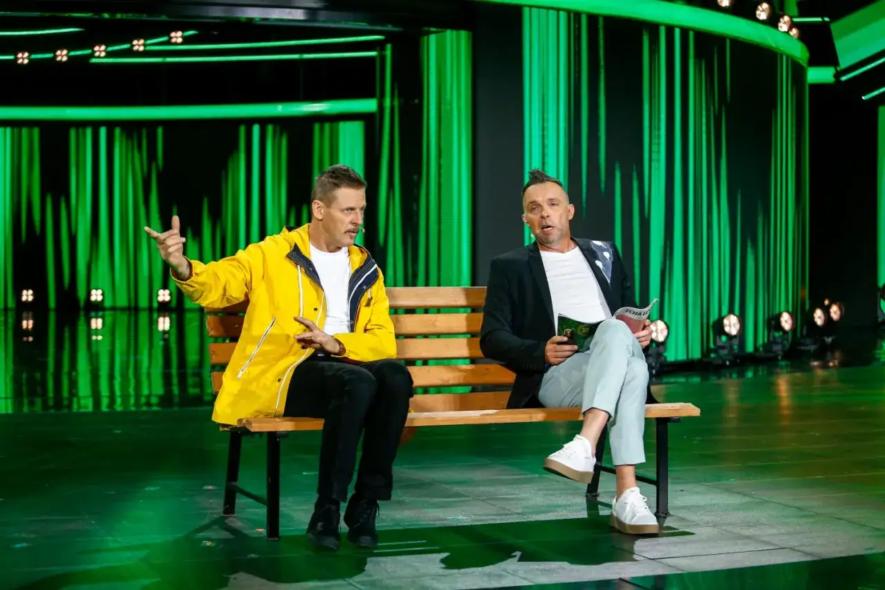 Kto występuje w kabarecie Ani Mru-Mru? Dwóch artystów siedzi na ławce na tle zielonej scenografii.