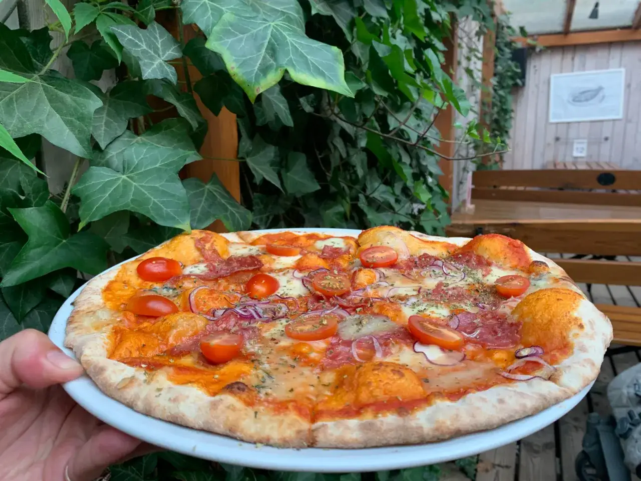 Pyszna pizza z pomidorkami i salami, idealna na pytanie gdzie zjeść w Dębkach.