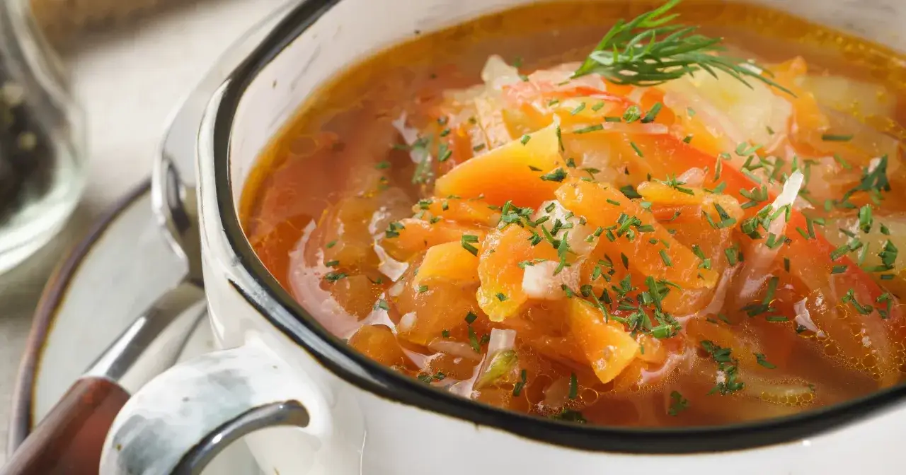 Aksamitny bulion z warzywami, posypany szczypiorkiem. Czy zupy mają dużo kalorii? Ta wygląda na lekką i zdrową.