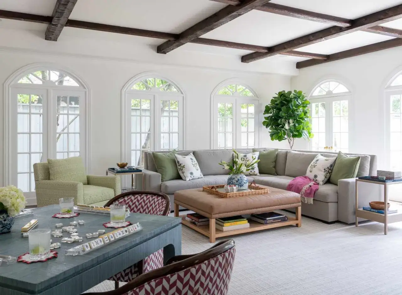 Jasne wnętrza inspiracje: przestronny salon z szarą kanapą, zielonymi akcentami i drewnianymi belkami na suficie.