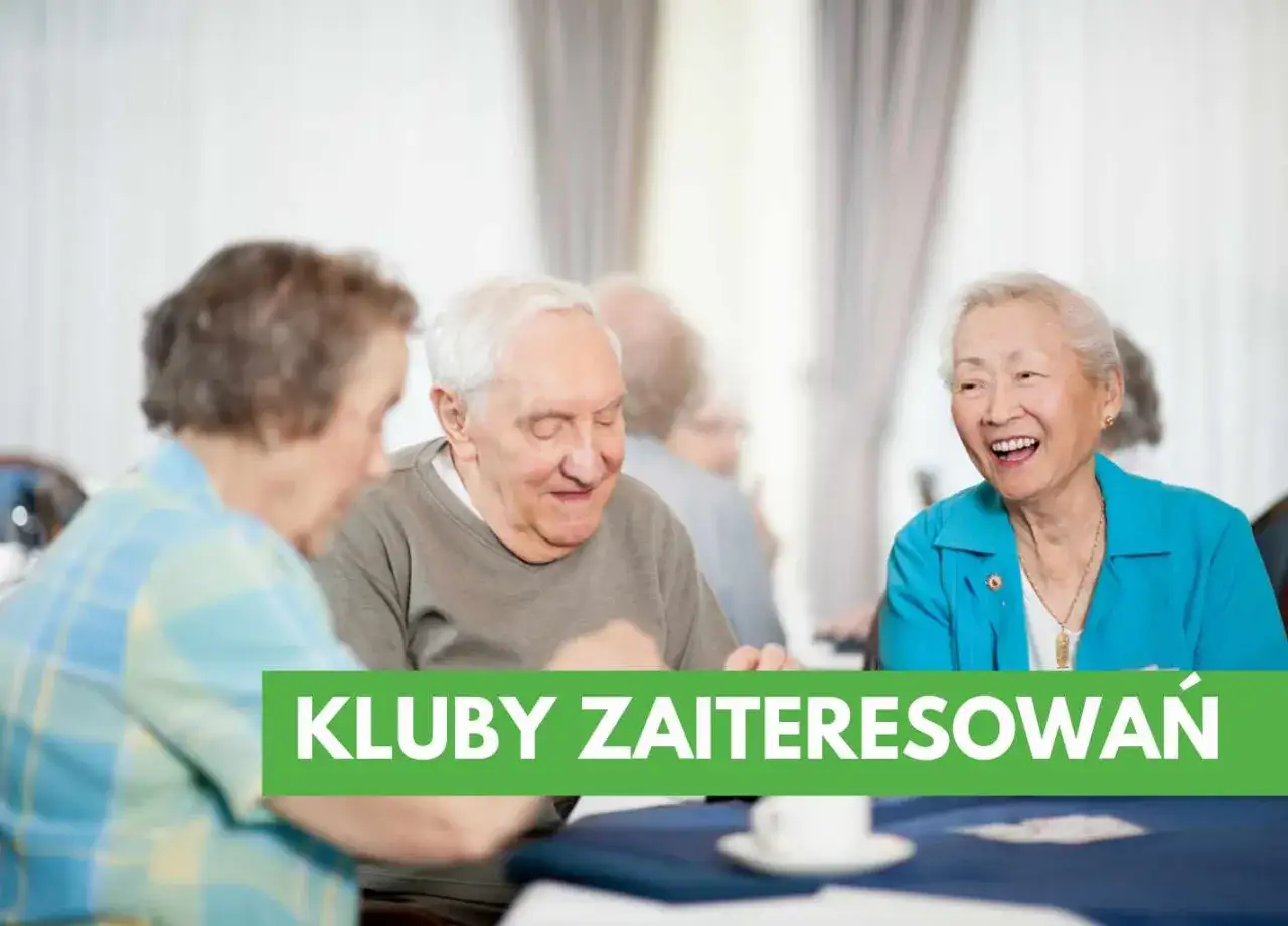 Uśmiechnięci seniorzy przy stole, dyskutujący o tym, jak założyć klub seniora. Zielony pas z napisem