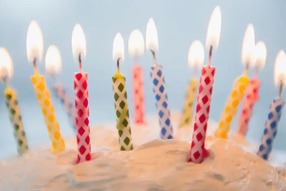 szczęśliwy senior lub seniorka w dniu 90 urodzin podczas zdmuchiwania świeczek na torcie