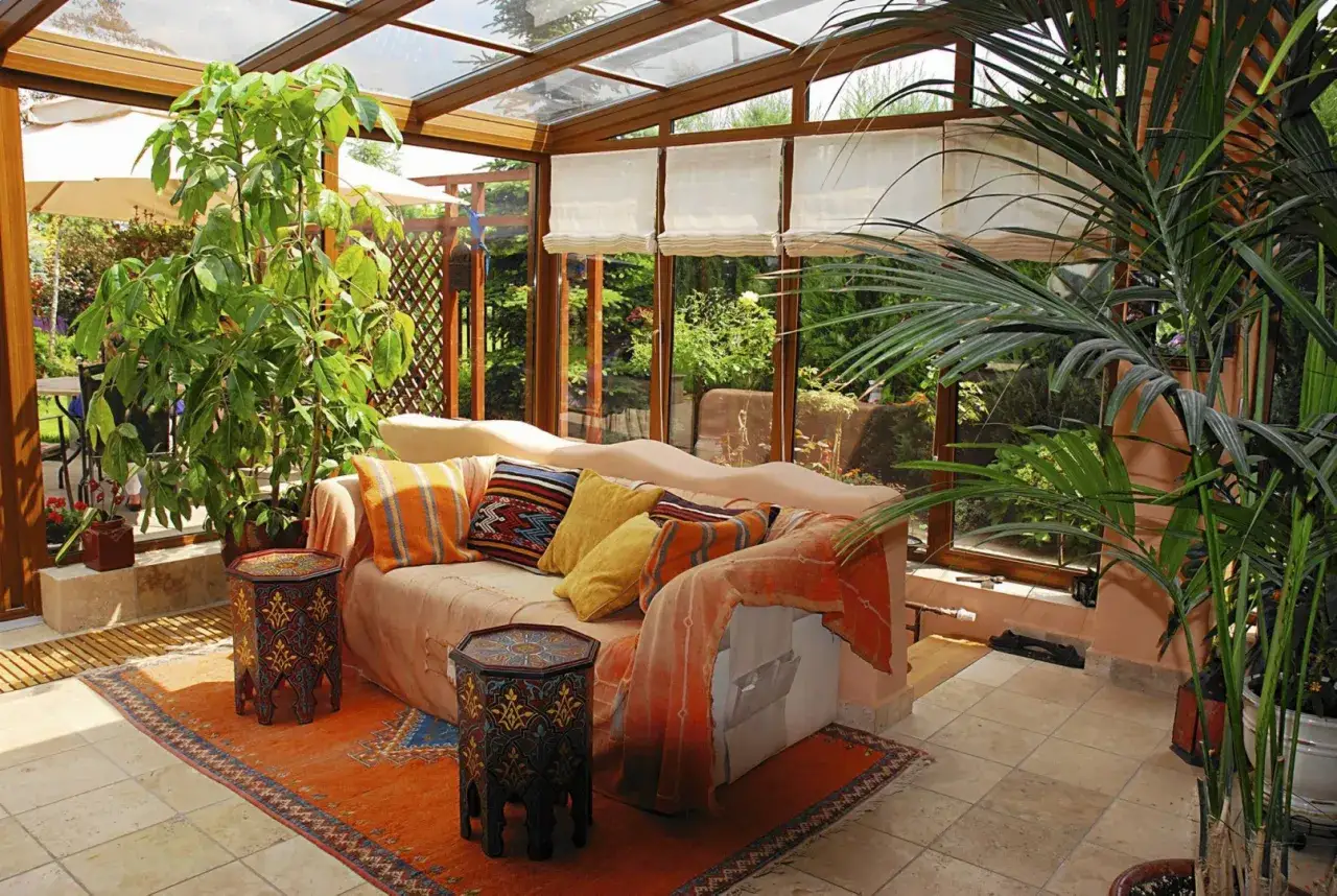 Wygodna sofa i rośliny w przeszklonym ogrodzie zimowym do samodzielnego montażu.