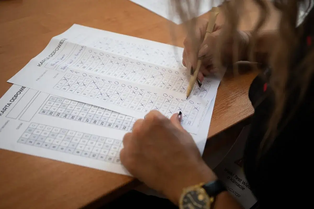 Osoba zaznacza odpowiedzi na karcie testowej, co pokazuje, jak oceniany jest egzamin zawodowy praktyczny.