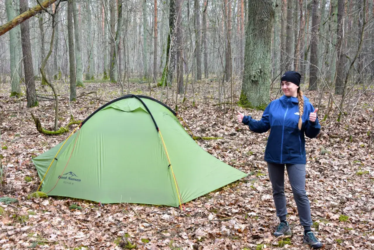 Dziewczyna z kciukami w górze przy zielonym namiocie w lesie. Idealne miejsce, gdzie pod namiot Śląskie.