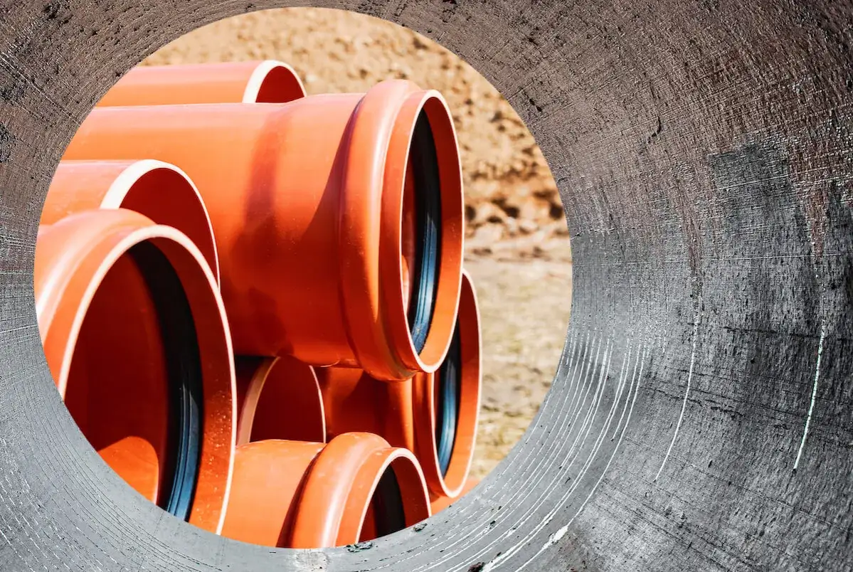 Pomarańczowe rury kanalizacyjne czekają na zabudowę rowu melioracyjnego.