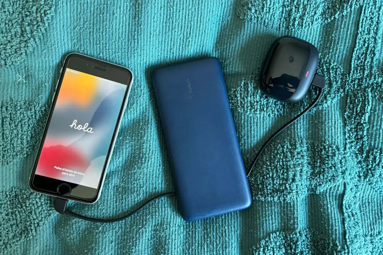Różne typy ładowarek do telefonów: powerbank Belkin, ładowarka samochodowa i iPhone z kablem.