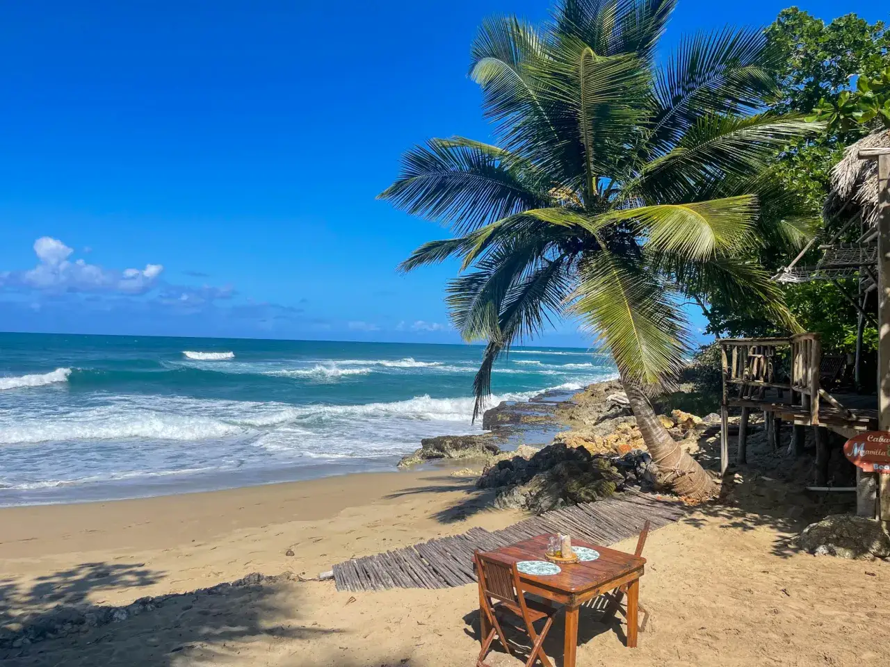 Idealny stolik na plaży na Dominikanie w kwietniu. Palmy, ocean i spok&oacute;j.