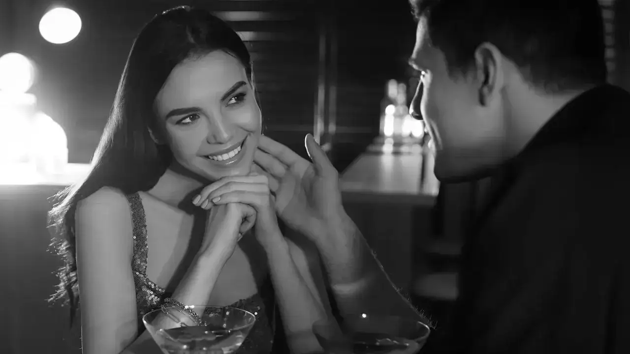 Uśmiechnięta kobieta patrzy na mężczyznę, kt&oacute;ry delikatnie dotyka jej policzka. To subtelne triki działające na mężczyzn, kt&oacute;re tworzą intymną atmosferę.