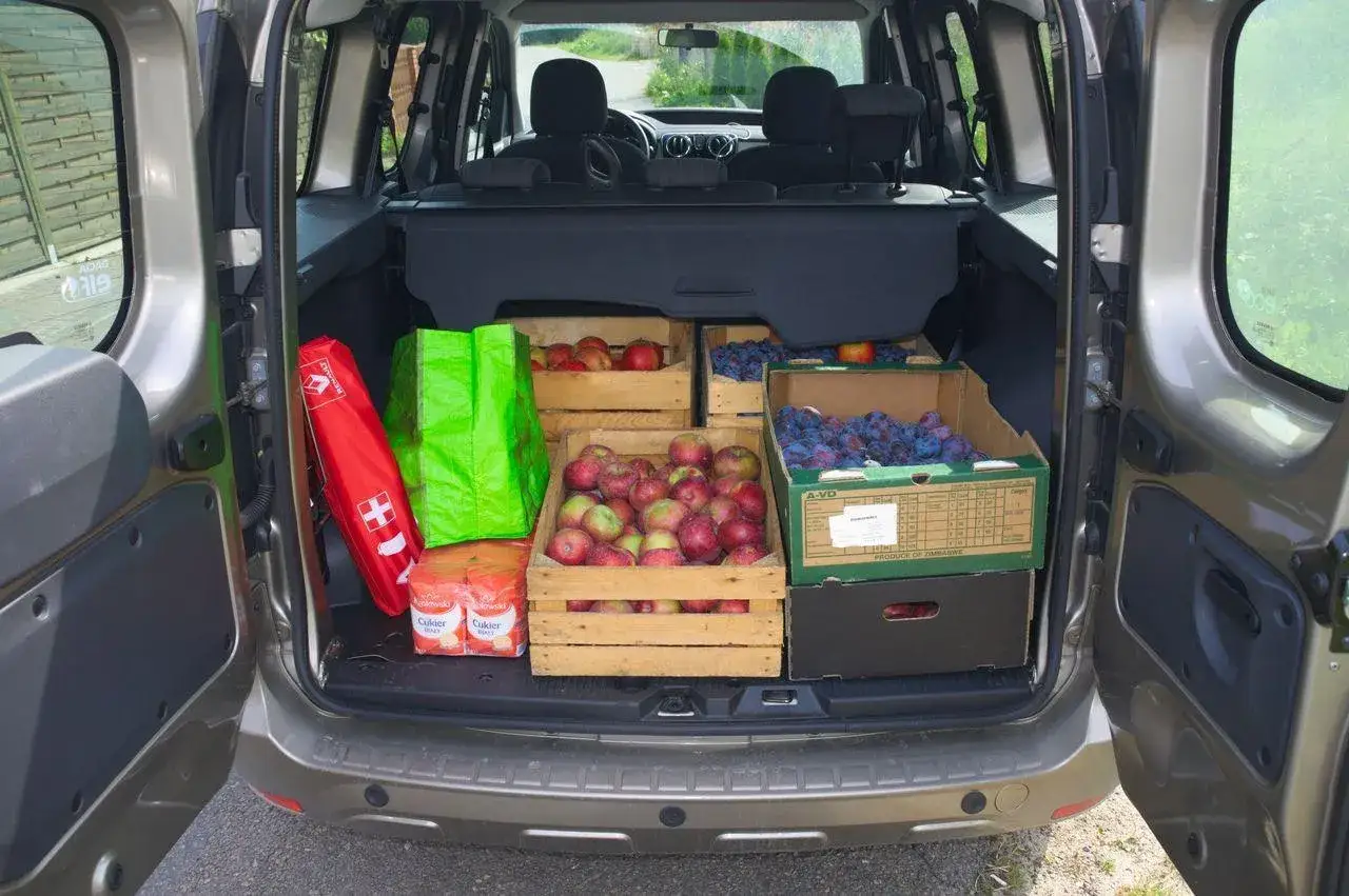 Dacia Dokker Stepway załadowana jabłkami i śliwkami. W bagażniku apteczka, torby i cukier.