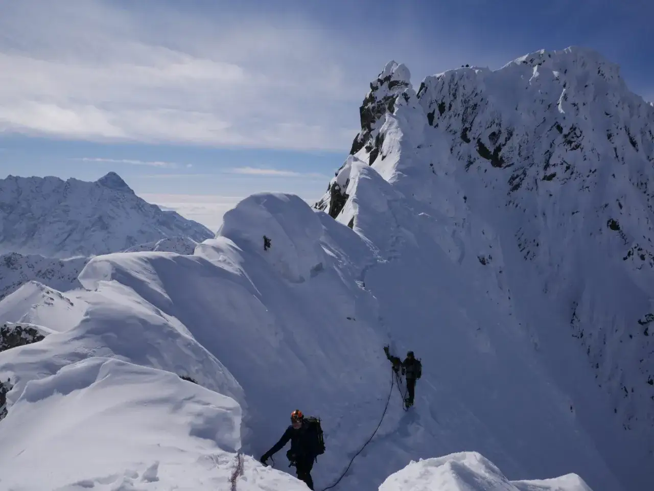 Zimowa wyprawa na Orlą Perć. Dw&oacute;ch alpinist&oacute;w wspina się po zaśnieżonym grzbiecie, pokonując trudny teren.