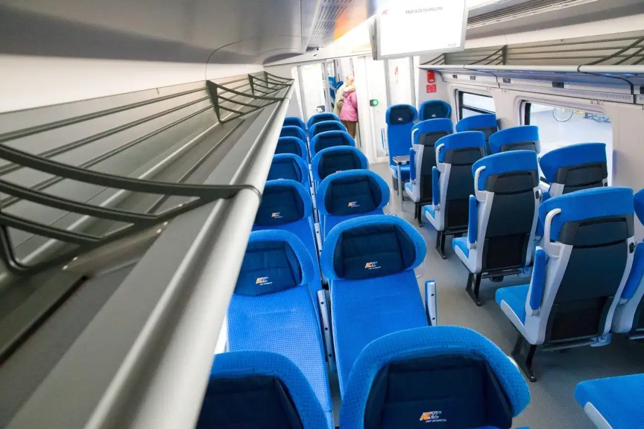 Wnętrze pociągu EIP z niebieskimi siedzeniami. Czy pociąg EIP to Pendolino? Tak, to nowoczesny pociąg Pendolino PKP Intercity.