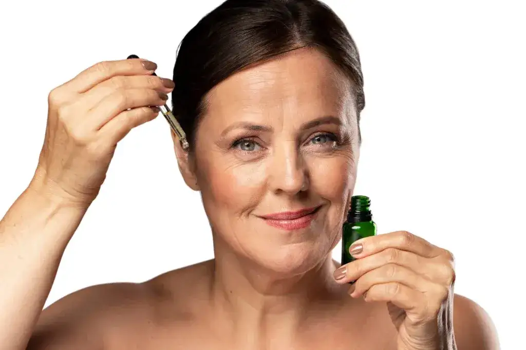 kobieta z cerą dojrzałą nakładająca olejek na twarz