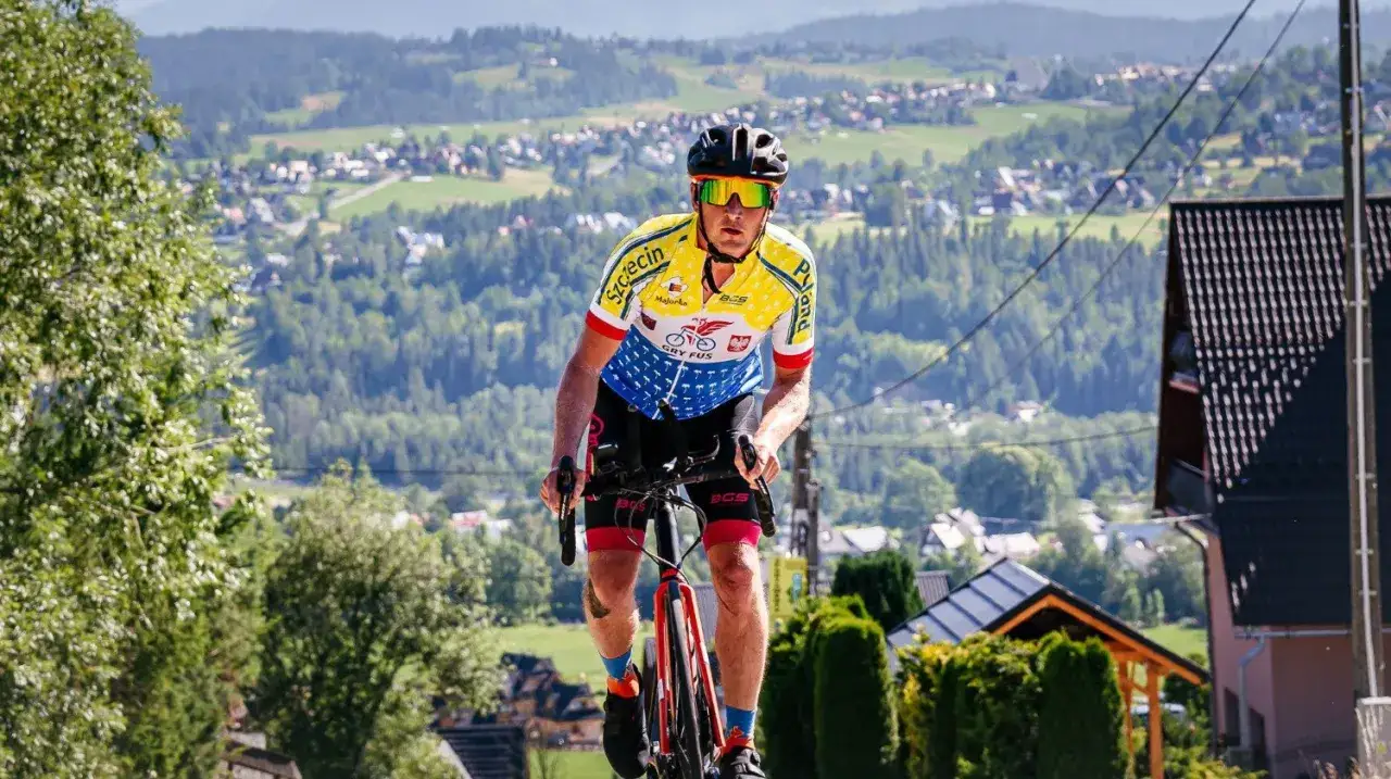 Kolarz w barwnym stroju ściga się w maratonie rowerowym, pokonując górskie podjazdy.