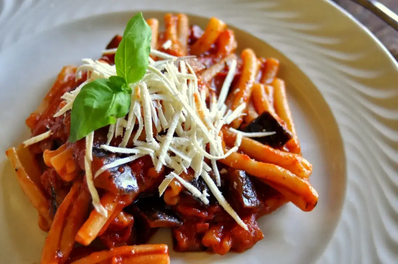 Rigatoni alla norma z bakłażanem, pomidorami i bazylią, posypane startym serem.