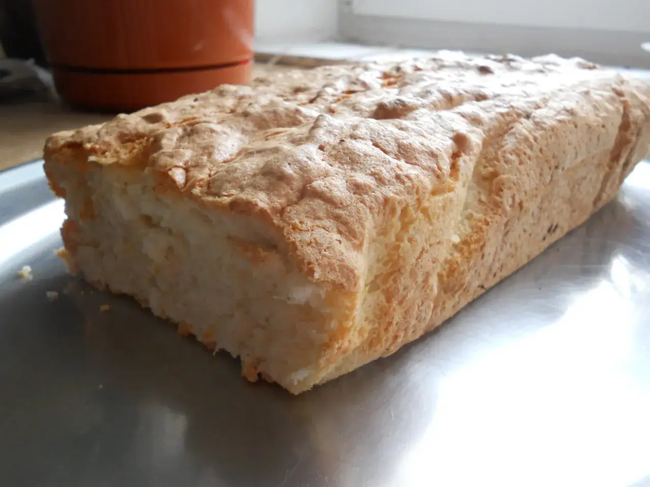 Puszyste ciasto z białek i kokosu, lekko zarumienione, leży na metalowej tacy.