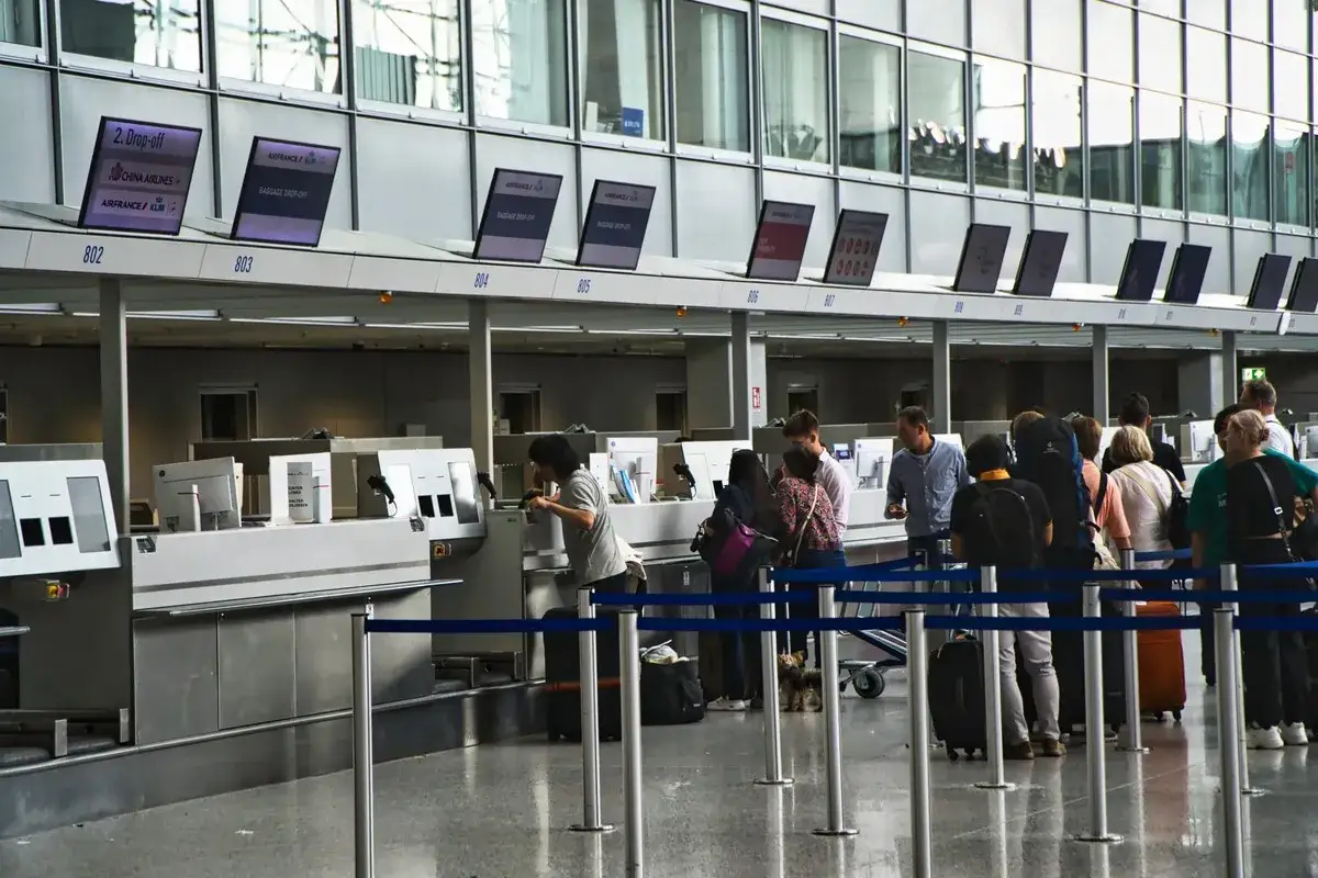 Kolejka do odprawy na lotnisku. Ludzie z bagażami czekają, by nadać walizki. To przypomina, co to jest turystyczny fundusz gwarancyjny.