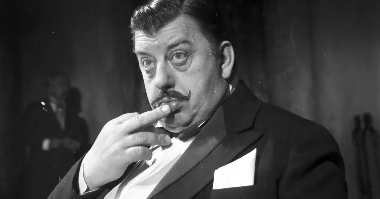 Mariusz Dmochowski w eleganckim smokingu, z charakterystycznymi wąsami, zastanawia się nad kolejną rolą w swoich filmach.