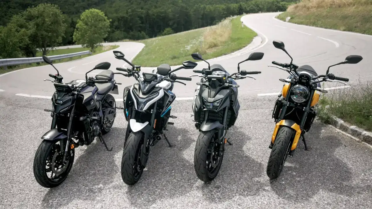 Cztery motocykle neked stojące na zakręcie górskiej drogi, gotowe do jazdy.