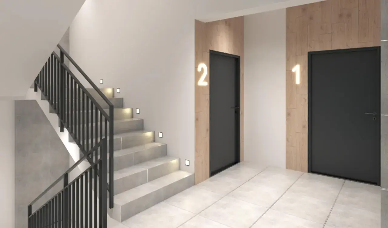 Nowoczesne oświetlenie klatki schodowej w bloku. Stopnie schod&oacute;w oświetlone dyskretnymi punktami, obok drzwi z numerami 1 i 2.