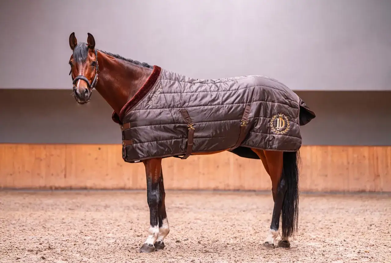 Brązowa derka na konia z ozdobnym logo i futrzanym kołnierzem, podkreślająca elegancję zwierzęcia.