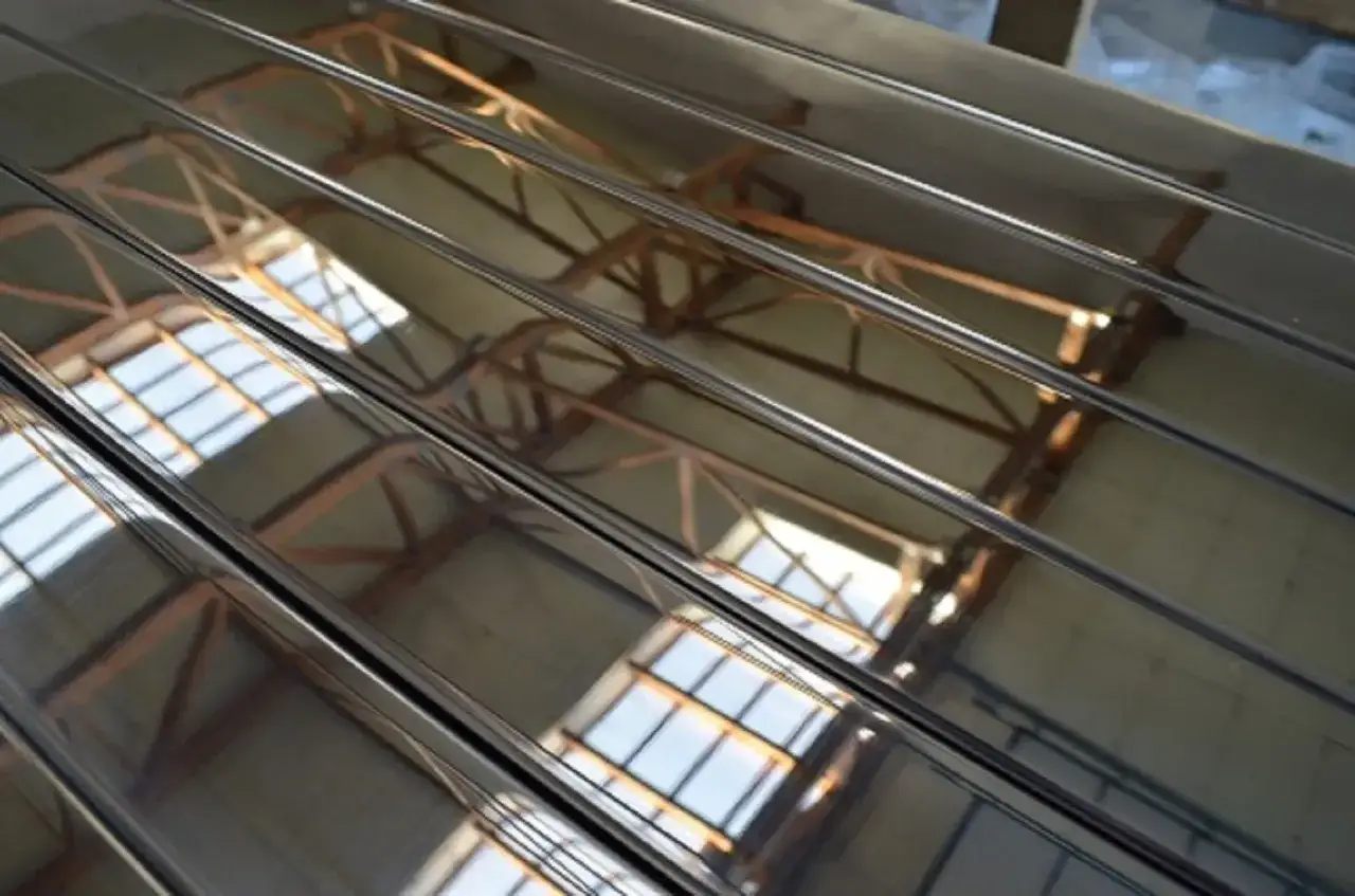 Błyszczące linie polerowanej stali nierdzewnej odbijają konstrukcję dachu hali.